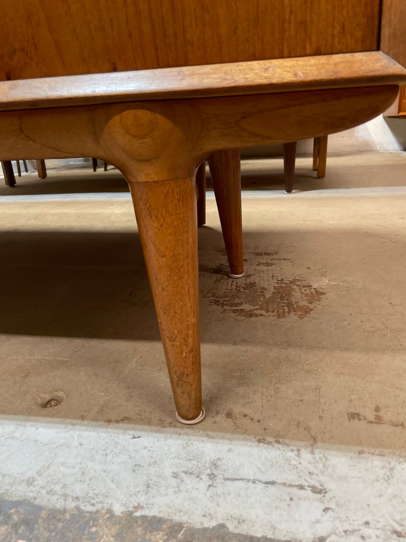 May include: Close-up of the bottom of a wooden cabinet with rounded legs and white protective pads on the bottom.