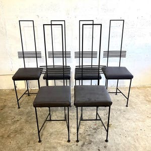 May include: Set of six black metal chairs and stools. The chairs have tall, rectangular backs with horizontal bars. The seats are square and upholstered in a dark gray material. The stools are also square with matching upholstery.