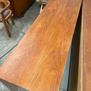 May include: A close-up of a wooden cabinet top with a rich brown finish. The wood grain is visible and the surface is smooth.