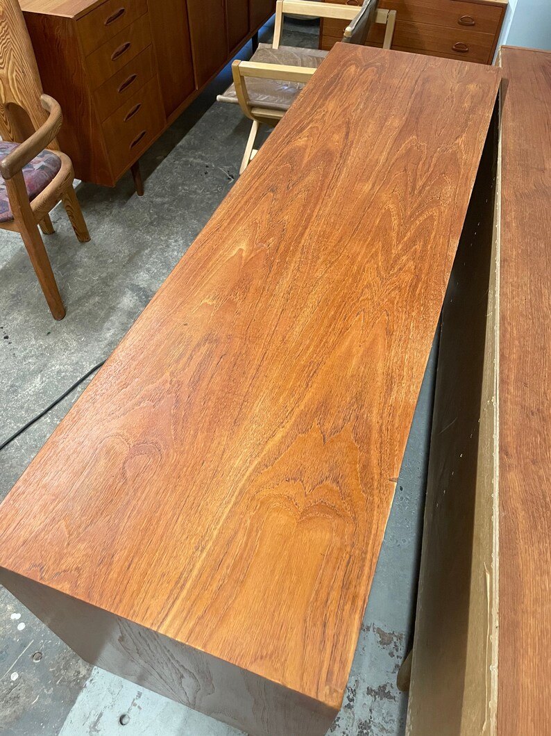 May include: A close-up of a wooden cabinet top with a rich brown finish. The wood grain is visible and the surface is smooth.