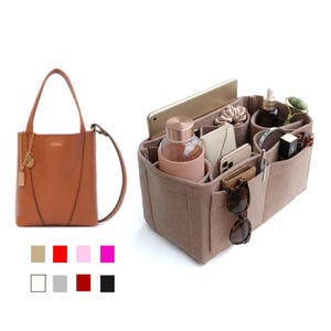 May include: A brown leather tote bag with a shoulder strap and a matching felt handbag organizer. The organizer has multiple compartments for items like a tablet, water bottle, and sunglasses. Color swatches are shown below the bag.