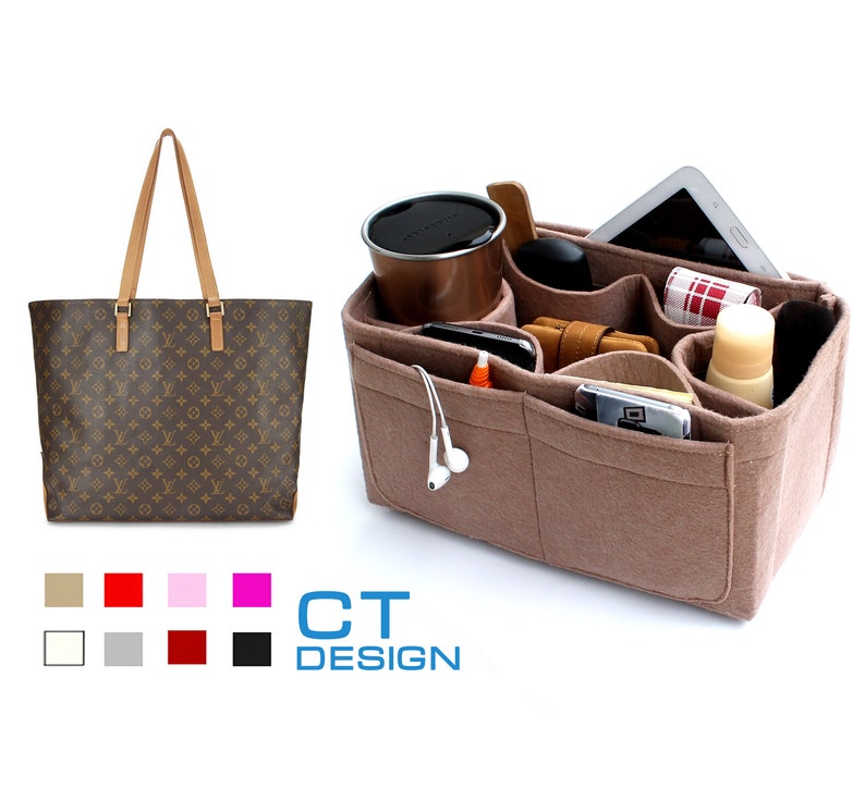 May include: A brown and tan tote bag with a monogram pattern. The bag is open and a beige felt organizer with multiple pockets is inside. The organizer is filled with various items, including a phone, a tablet, a coffee cup, and a small bottle of lotion.