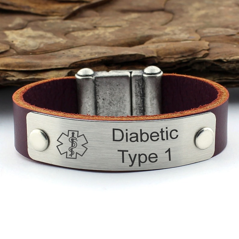 May include: A brown leather bracelet with a silver metal plate engraved with a medical symbol and the text "Diabetic Type 1".