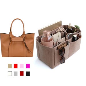 May include: A tan leather tote bag with a matching interior organizer. The tote has two handles and a decorative tassel. The organizer is made of a felt material and has multiple compartments for items like a tablet, water bottle, and sunglasses.