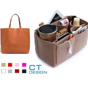 Peut inclure: Un sac fourre-tout en cuir marron avec un organiseur en feutre. L'organisateur comporte plusieurs compartiments pour transporter des objets tels qu'un téléphone, une tablette, une bouteille d'eau et d'autres accessoires.