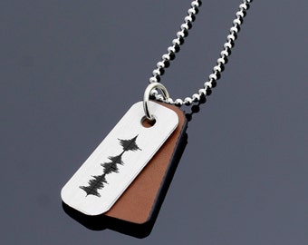 May include: Silver chain necklace with a brown leather and silver tag pendant. The silver tag has a sound wave design engraved on it.