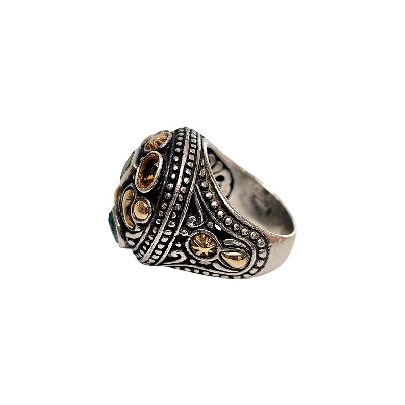 May include: A silver ring with a large, ornate setting featuring green and yellow gemstones and gold accents.