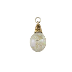 May include: A gold pendant with a white iridescent glass orb. The orb is filled with small white and iridescent flakes. The pendant has a gold bail.