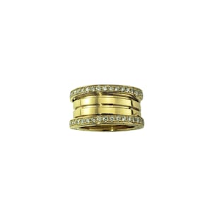 May include: A gold-colored ring with a multi-layered design. Each layer is adorned with small, clear gemstones. The ring has a polished finish, reflecting light. The overall design is modern and elegant, suitable for various occasions.