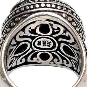 May include: Close-up of the inside of a silver ring with an intricate design and the inscription "925" on the back.