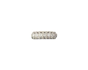 May include: A silver band ring with a row of round clear stones set in a decorative pattern.