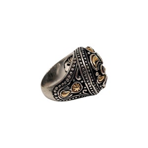 May include: A silver ring featuring a large, round, faceted gemstone set in a gold-toned bezel. The ring is adorned with intricate, detailed designs in silver and gold.