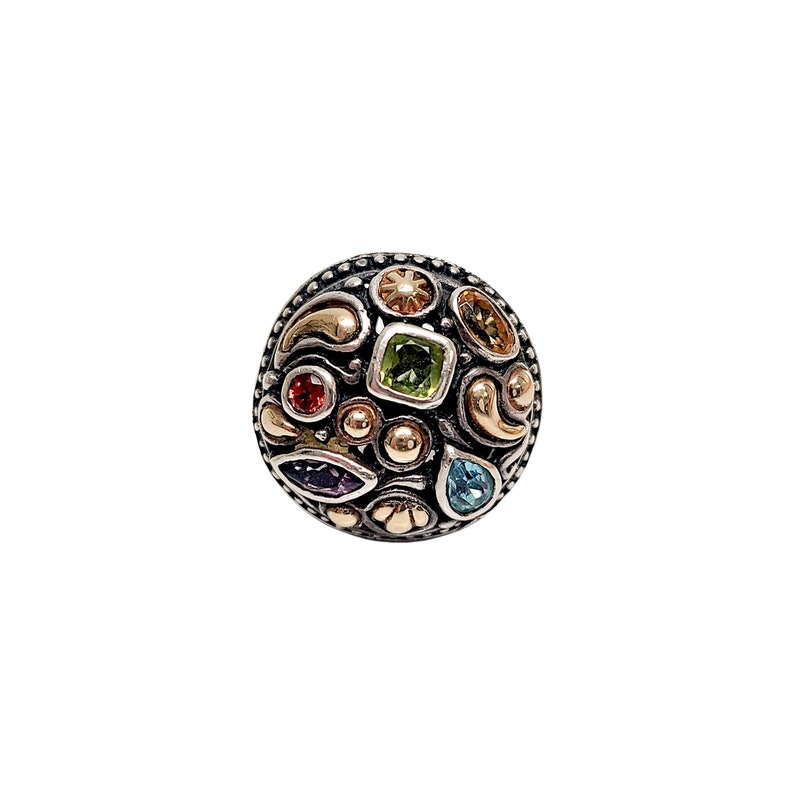 May include: A silver ring featuring a round, multi-coloured gemstone design. The ring has a variety of small, colourful gemstones set in a silver and gold setting.