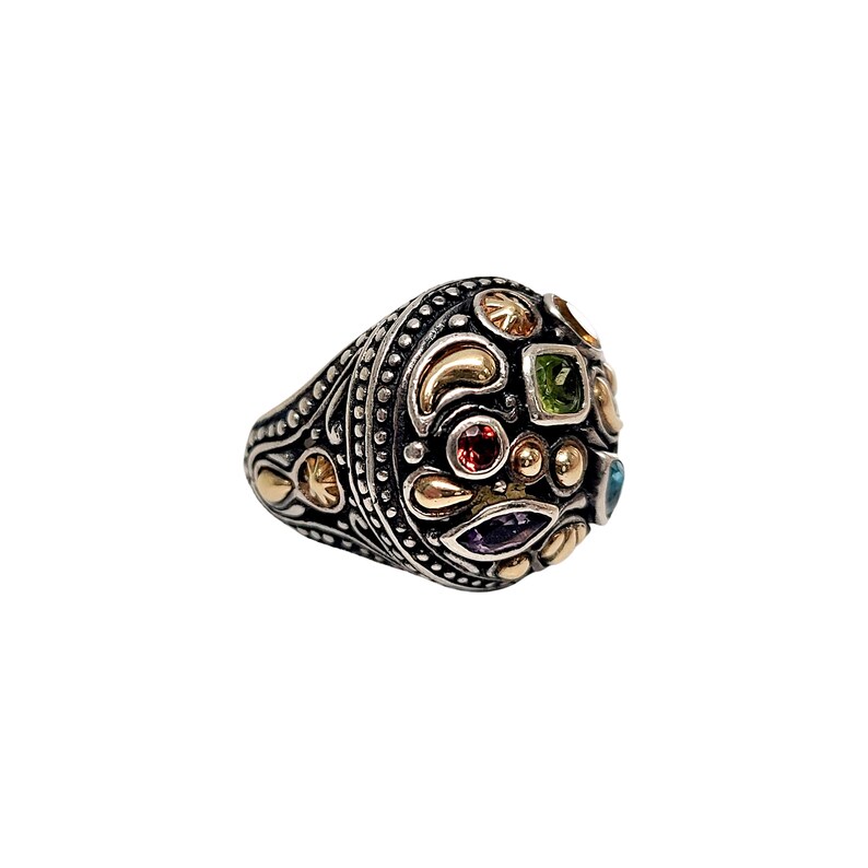 May include: A silver ring with a round, multi-coloured gemstone setting. The ring is decorated with intricate details and features a variety of gemstones, including green, red, purple, and blue.