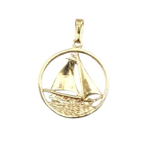 May include: A gold-toned pendant featuring a sailboat in a circle with a textured water design.