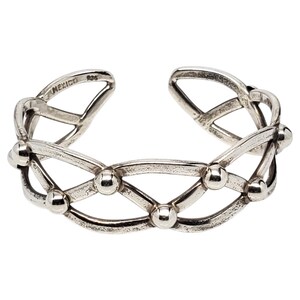 May include: A silver cuff bracelet featuring an openwork lattice design with small spherical accents at each intersection. The interior of the band is stamped with the text MEXICO and 925, indicating the origin and sterling silver composition.
