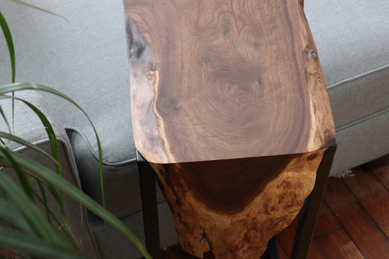 May include: A wooden side table with a live edge top and black metal legs. The wood has a rich brown color and a natural grain pattern.