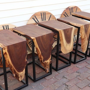 May include: Five wooden end tables with live edge tops and black metal frames. The tables are arranged in a row on a brick patio.