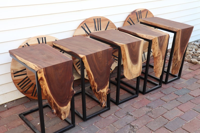 May include: Five wooden end tables with live edge tops and black metal frames. The tables are arranged in a row on a brick patio.