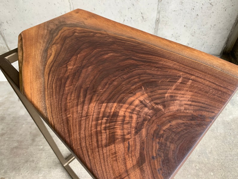 May include: A dark brown wooden table top with a natural wood grain pattern. The table top is supported by a metal frame.