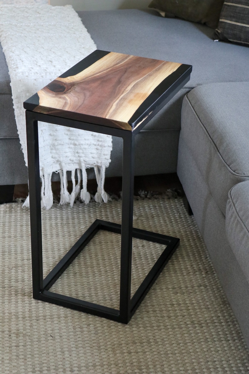 May include: A black metal side table with a live edge walnut wood top and black epoxy resin inlay. The table is sitting on a gray rug.