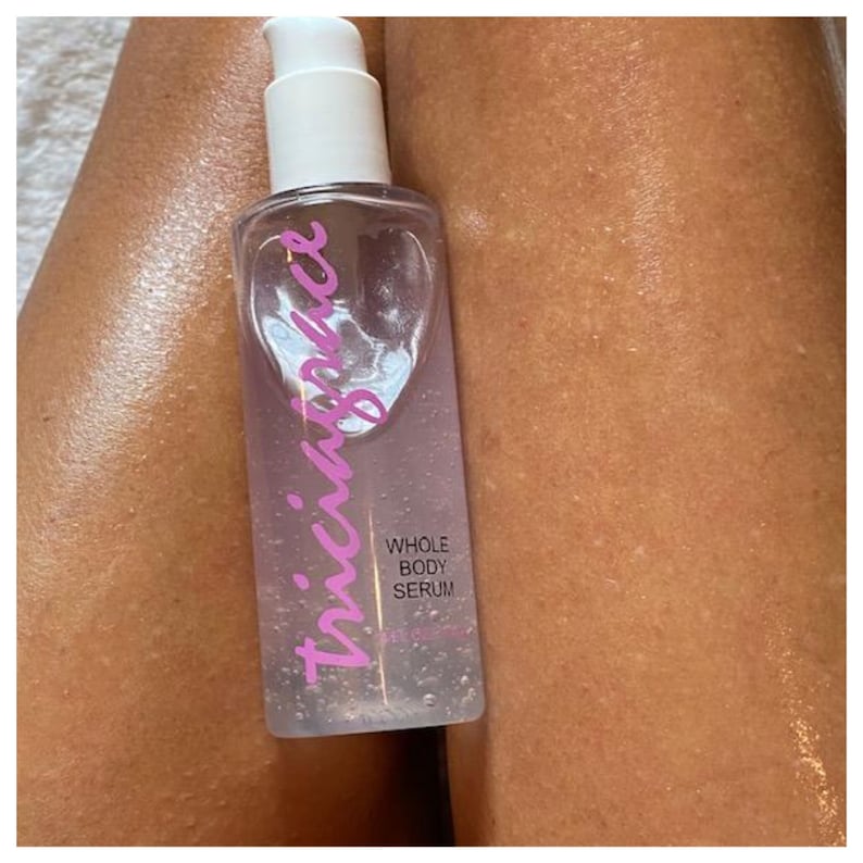 May include: A clear glass bottle with a white pump top and pink lettering that reads "thicc.bounce" on the front. The bottle contains a clear liquid and the label also reads "Whole Body Serum".