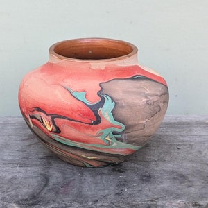 May include: A small, round, red, brown, black, and green ceramic vase with a marbled design.