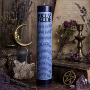 May include: A tall, dark purple pillar candle featuring a light blue label with the text Kentucky Conjure Wiccan Rede printed in black. The candle has a cylindrical shape with a flat top and a single white wick centered at the top.