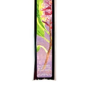 May include: Incense stick packaging with a floral design. The packaging shows a watercolour painting of pink and yellow flowers with green leaves on a purple background. Text on the package reads "20 COUNT 45 MINUTES PLANT-BASED."