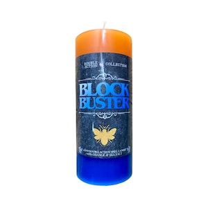 May include: A cylindrical candle with an orange top and blue base. The central section is dark with the words "BLOCK BUSTER" in blue. A gold butterfly graphic is below the text. The candle is labelled "DOUBLE ACTION COLLECTION".