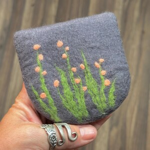 May include: A gray felt coin purse with a design of green leaves and orange flowers.