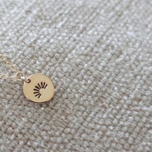 May include: A gold necklace with a small round pendant featuring a sun design.