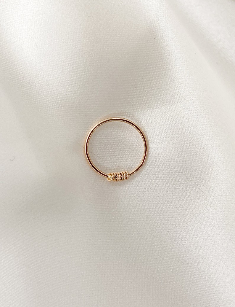 May include: A simple gold ring with a twisted detail.