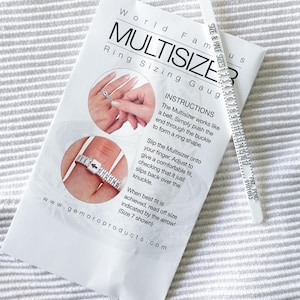 May include: White plastic ring sizer with a white measuring tape on the side. The tape measures ring sizes from 1 to 16. The text on the card reads "World Famous Multisizer Ring Sizing Gauge" and "Instructions: The Multisizer works like a belt. Simply push the end through the buckle to form a ring shape. Slip the Multisizer onto your finger. Adjust to give a comfortable fit, checking that it just slips back over the knuckle. When best fit is achieved, read off size indicated by the arrow! (Size 7 shown)" and "www.gemoroproducts.com".