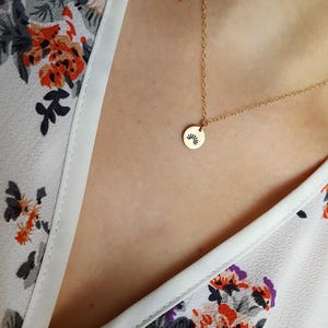 May include: A gold chain necklace with a small round pendant featuring a sunburst design.