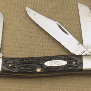 May include: A vintage pocket knife with three open stainless steel blades. The handle is dark brown with a textured pattern, silver end caps, and the "CASE" logo. Small brass rivets secure the handle.