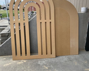 May include: Two wooden arch shapes, one with multiple arches cut out and the other with a single arch, both in a light brown color.