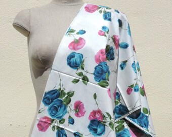 May include: White fabric with a blue and pink floral pattern. The fabric features a repeating pattern of blue roses with pink centers and green leaves.