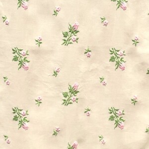 May include: A cream-colored fabric with a repeating pattern of small pink flowers and green leaves.