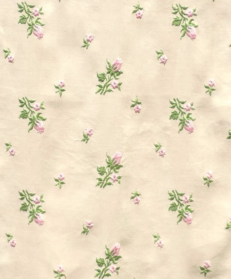 May include: A cream-colored fabric with a repeating pattern of small pink flowers and green leaves.