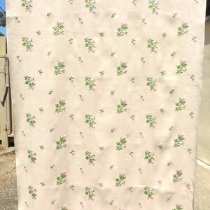 May include: A cream-colored fabric with a repeating pattern of pink and green embroidered flowers.