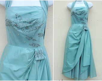 May include: A vintage halter-style dress in a light blue color with a beaded design on the bodice. The dress has a fitted bodice and a flowing skirt.