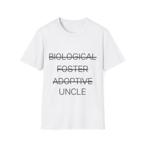 Op de afbeelding: Wit T-shirt met de woorden "BIOLOGICAL", "FOSTER", "ADOPTIVE" en "UNCLE" erop gedrukt. Het woord "BIOLOGICAL" is doorgestreept.