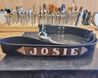 May include: Black leather dog leash with a brown leather name tag that says "JOSIE" in a Celtic knot design. The leash has a silver metal clip.