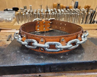 May include: A brown leather belt with a silver chain detail. The belt has multiple rows of rivets and a buckle.