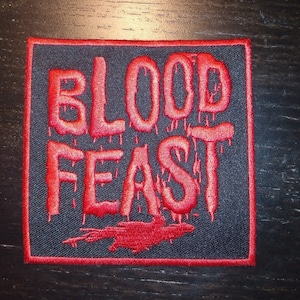 May include: Red embroidered patch with the words "BLOOD FEAST" in a dripping font on a black background.