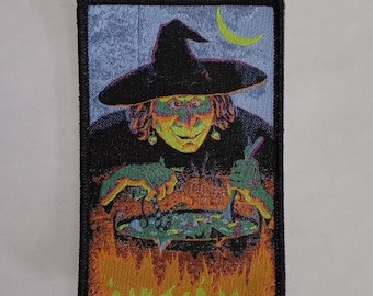May include: A witch with a green face and a black hat stirs a cauldron with a wooden spoon. The cauldron is over a fire and there is a crescent moon in the background.