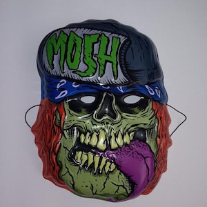 May include: A green, blue, and red plastic Halloween mask with a skull face and the word "Mosh" on the forehead. The mask has a bandana and a baseball cap.