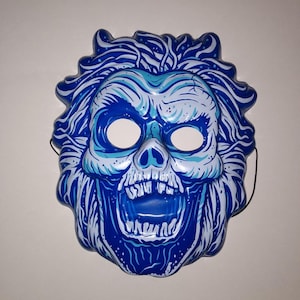 May include: A blue and white plastic Halloween mask of a skull with a wide open mouth and a wild, white hair design.