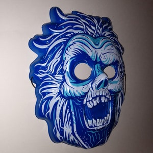 May include: A blue and white plastic Halloween mask of a skull with a wide open mouth and a wild, spiky hair design.